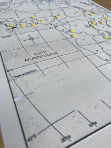 Closeup photo of a tactile graphic showing raised dots in braille and raised lines outlining a map.